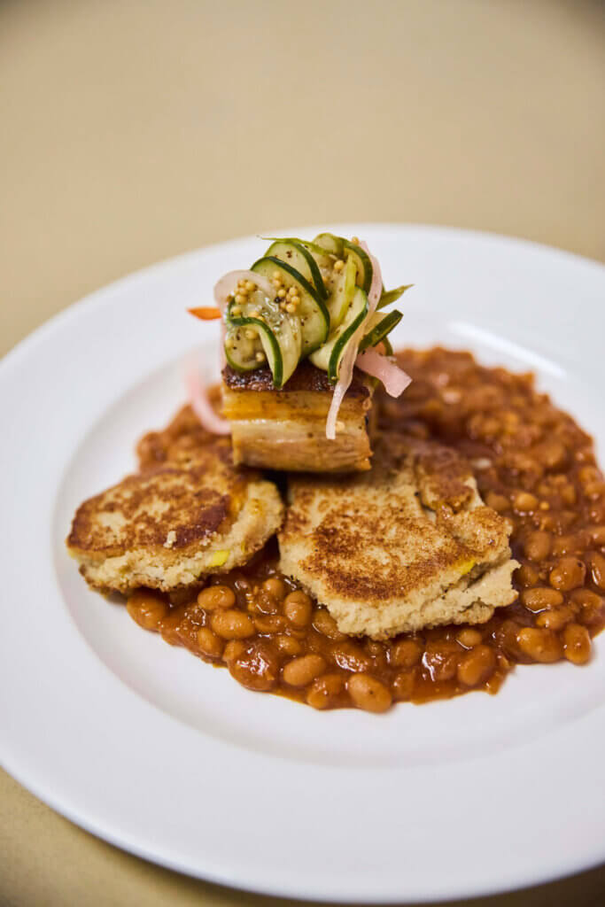 Strawberry black pepper Iberian Duroc pork belly with Boston baked beans, summer pickles, and Rhode Island johnnycakes