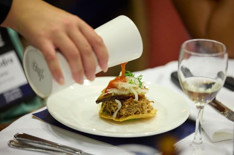 Pouring sauce over tostada